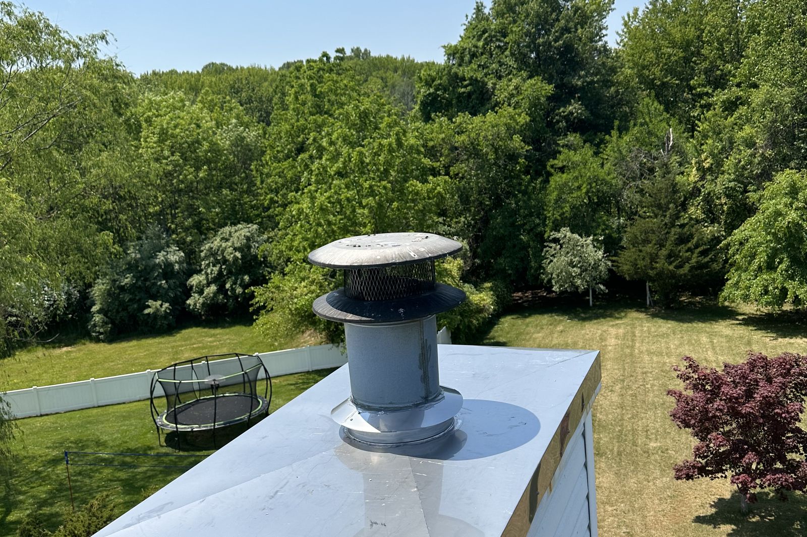 Stainless steel chimney cap installed on a metal roof cricket on a New Jersey home