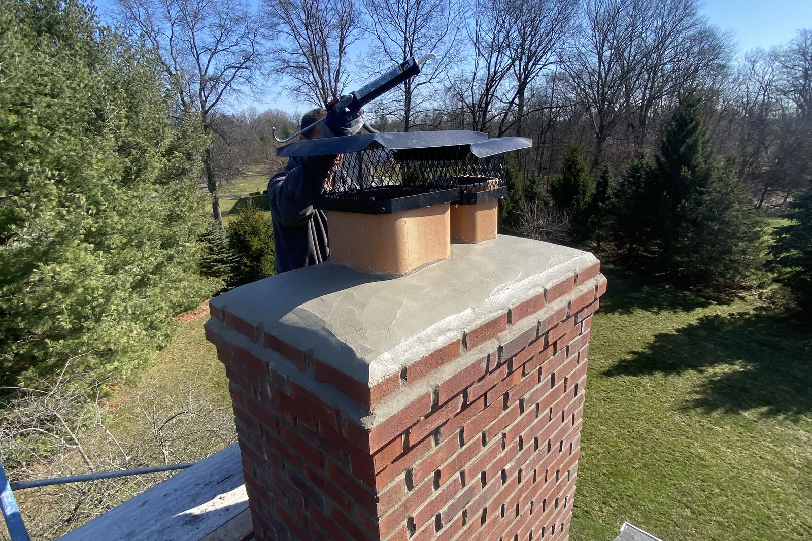 Ambassadors Construction technician sealing a new chimney cap on a New Jersey roof