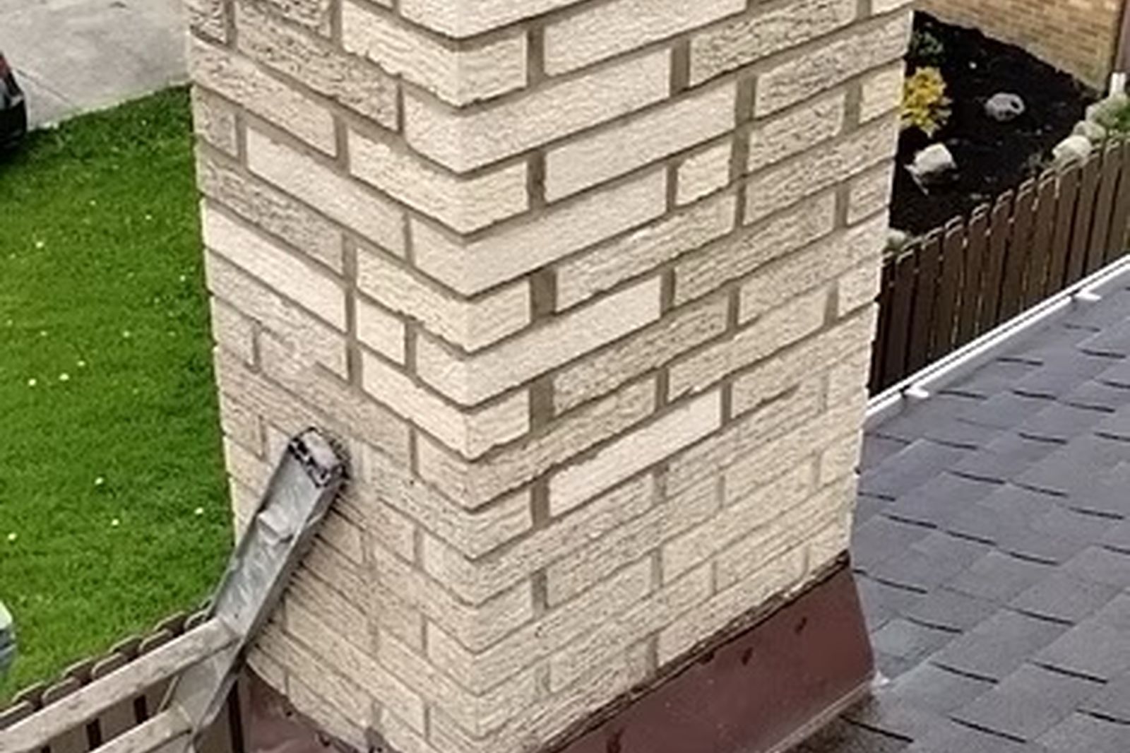 Repaired chimney with tan brick and new chimney cap on a New Jersey roof