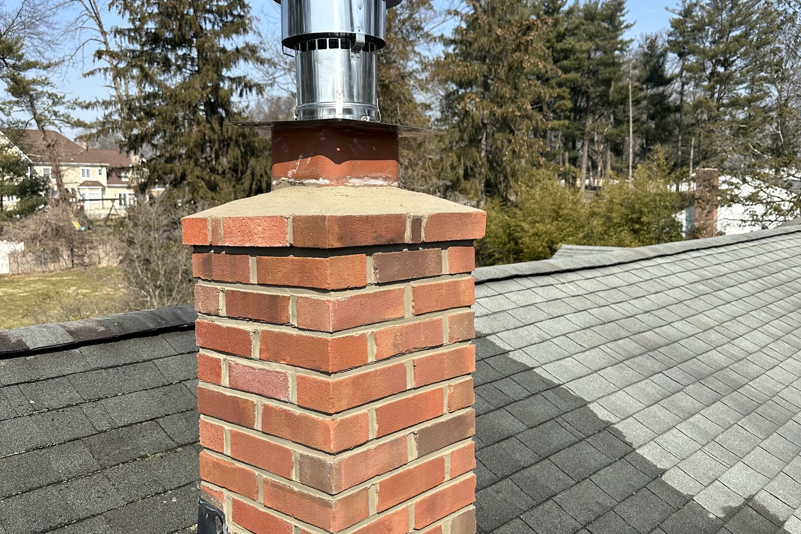 Finished chimney repair with new brick and cap on a New Jersey roof