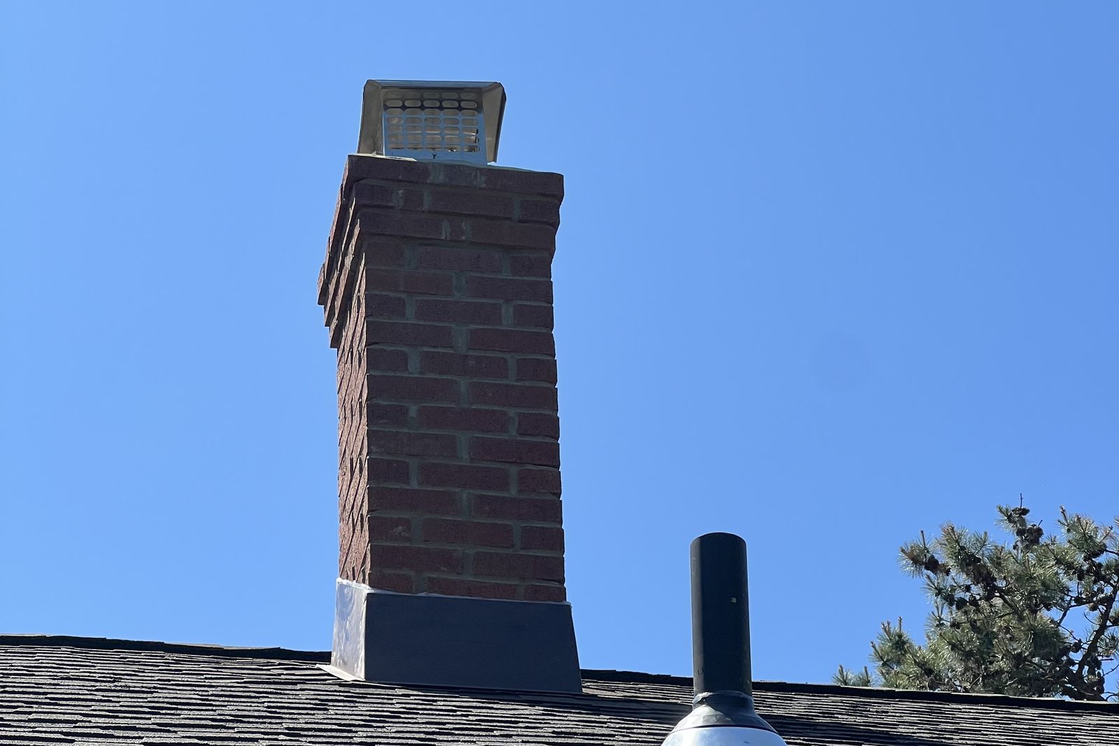 Finished brick chimney with new cap and roof vent pipe on a New Jersey home