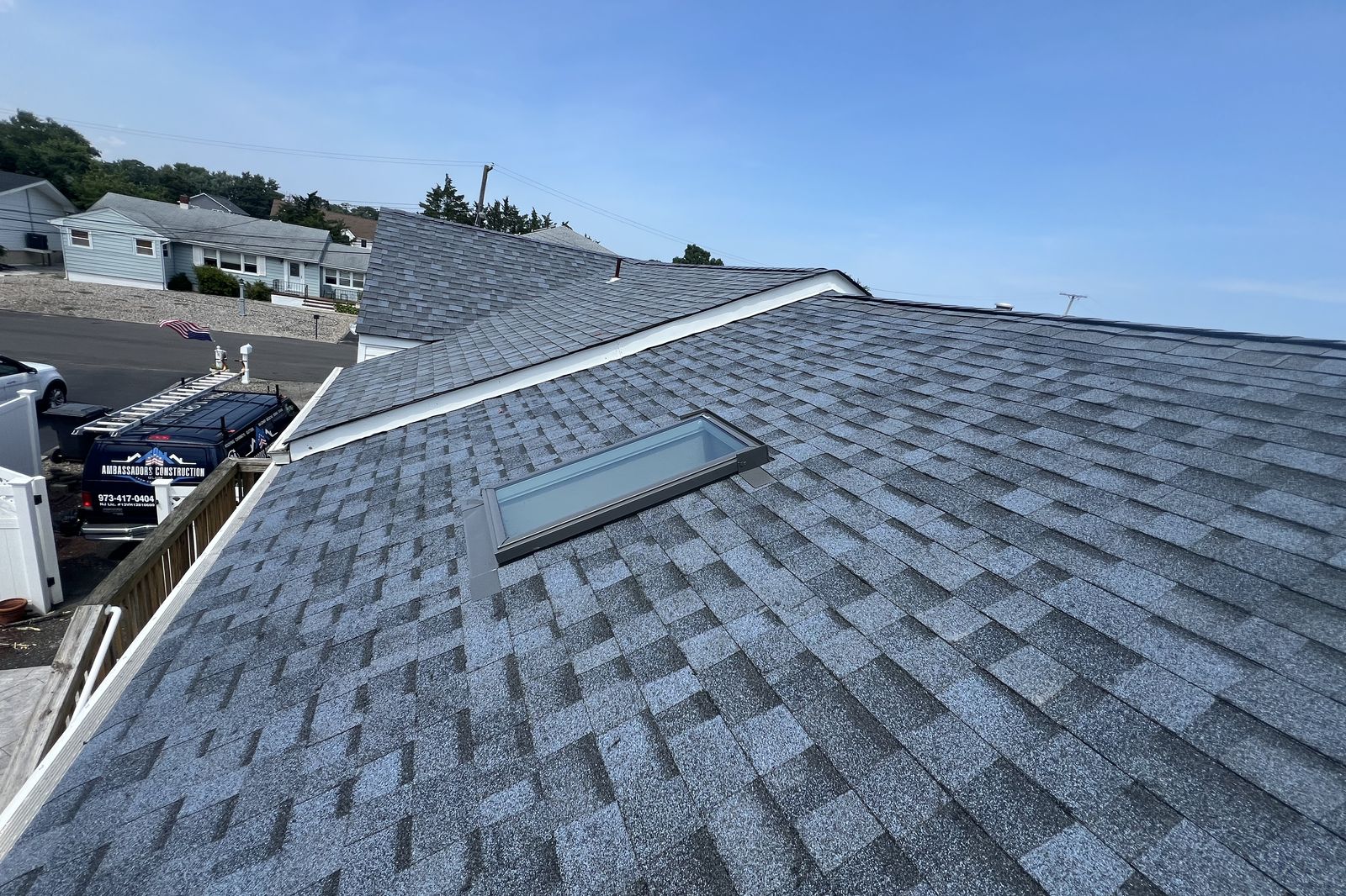 Wide view of a New Jersey roof with a newly installed skylight and Ambassadors Construction van