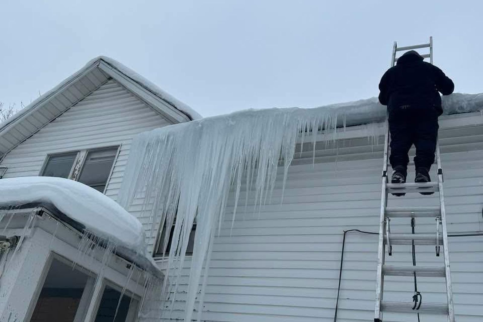 Ambassadors Construction technician addressing a large ice dam and icicles on a New Jersey home's gutters