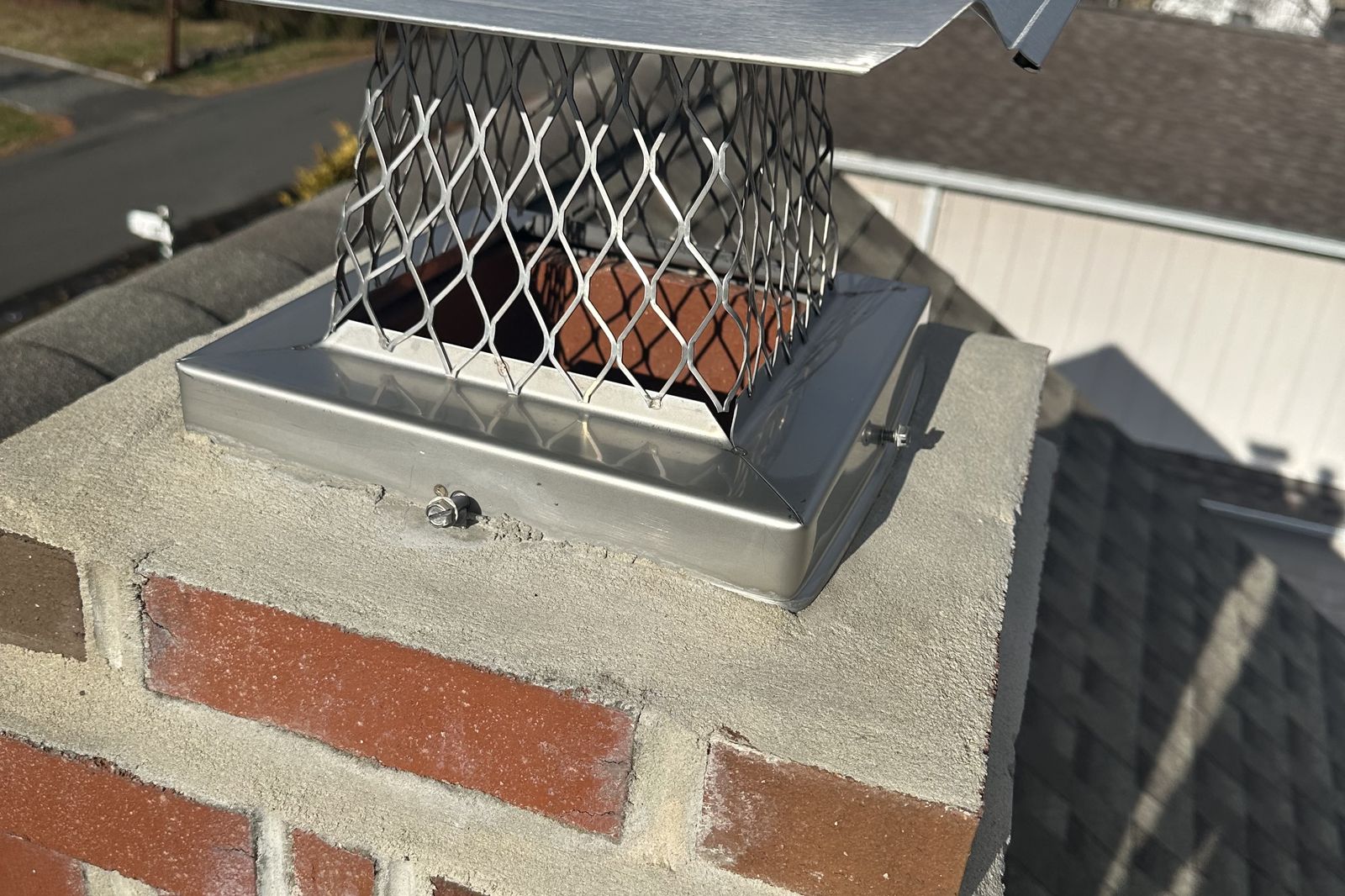 Close-up of a new stainless steel chimney cap installed on a New Jersey home