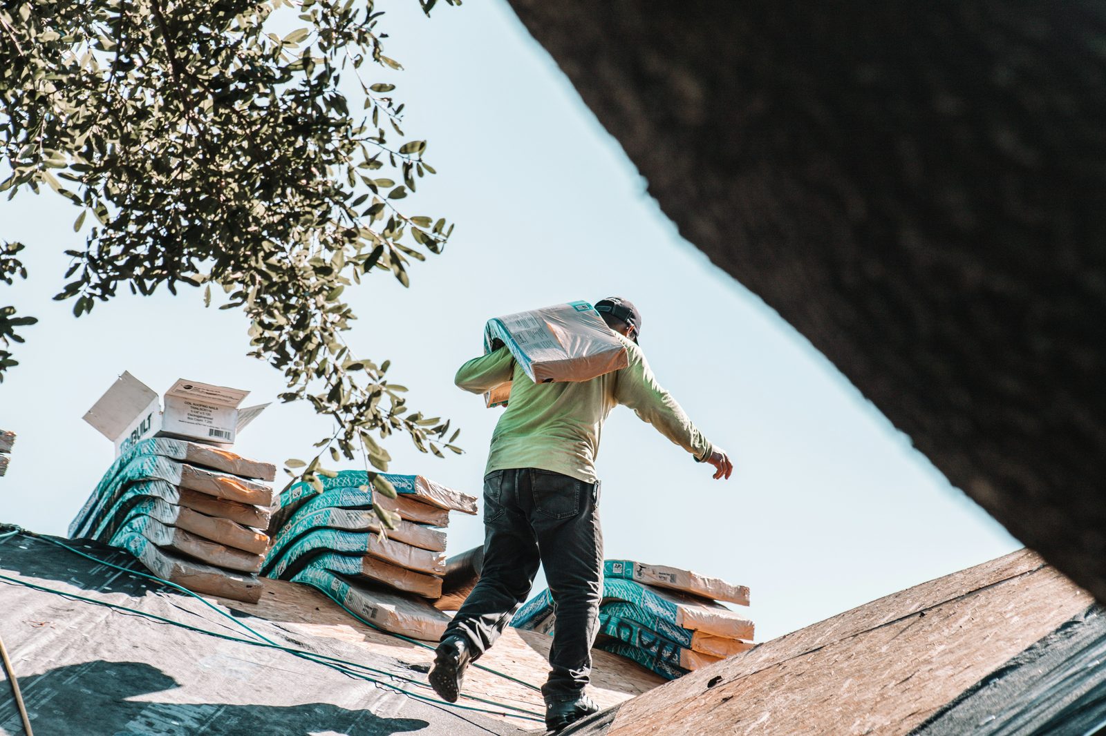 Roofing contractor carrying shingle bundles across a roof during installation in New Jersey