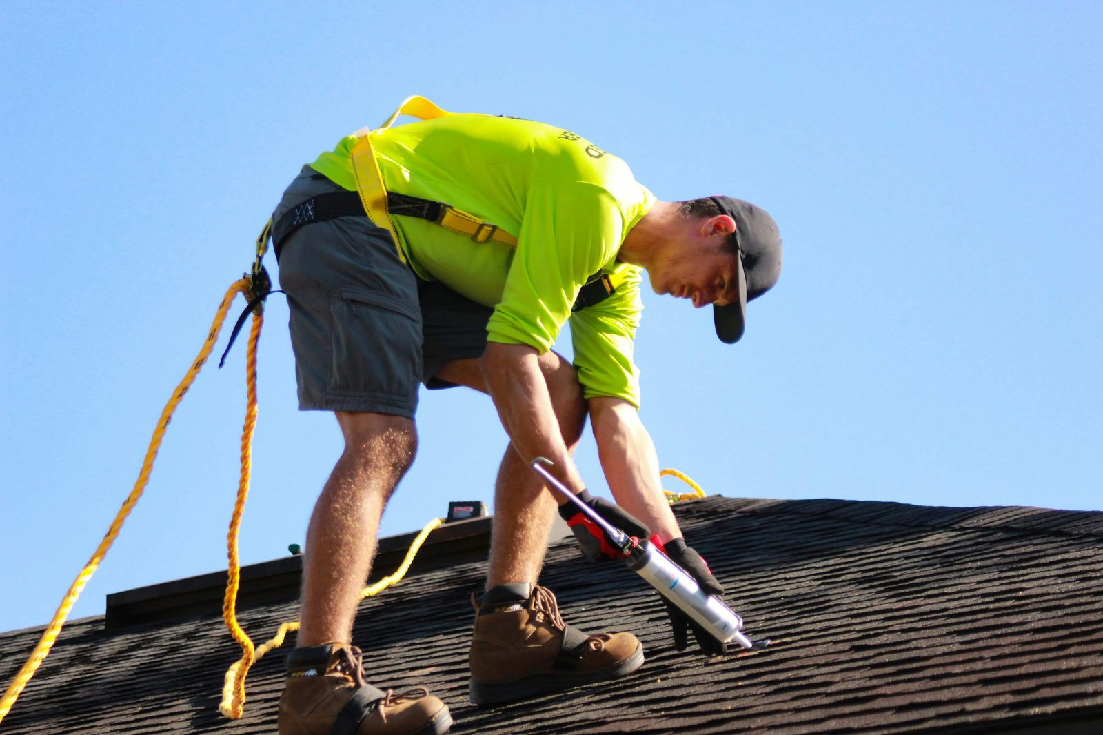 Roofing technician applying sealant during shingle roof repair in New Jersey
