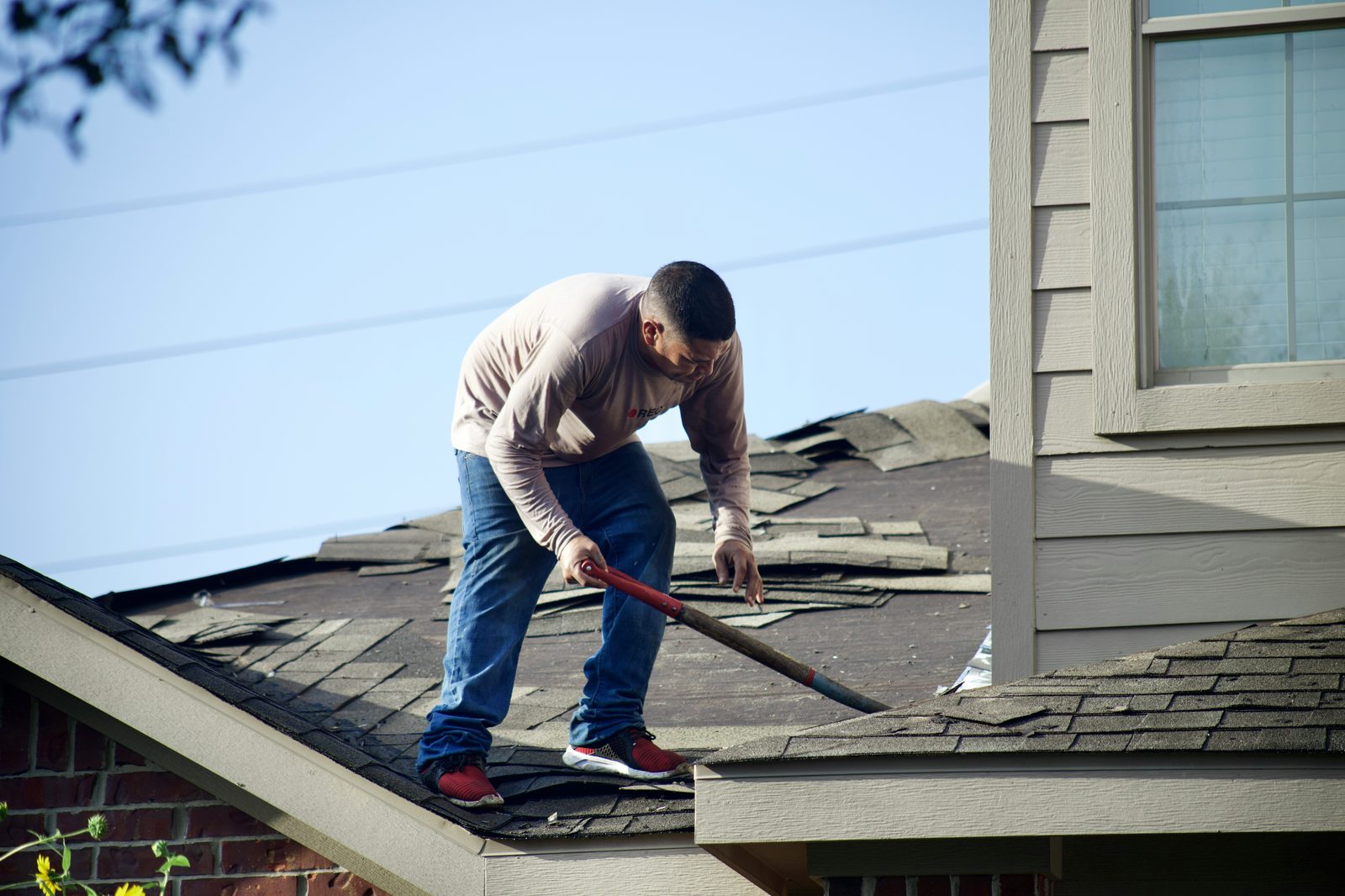 Roofing crew removing old shingles during a roof replacement in New Jersey