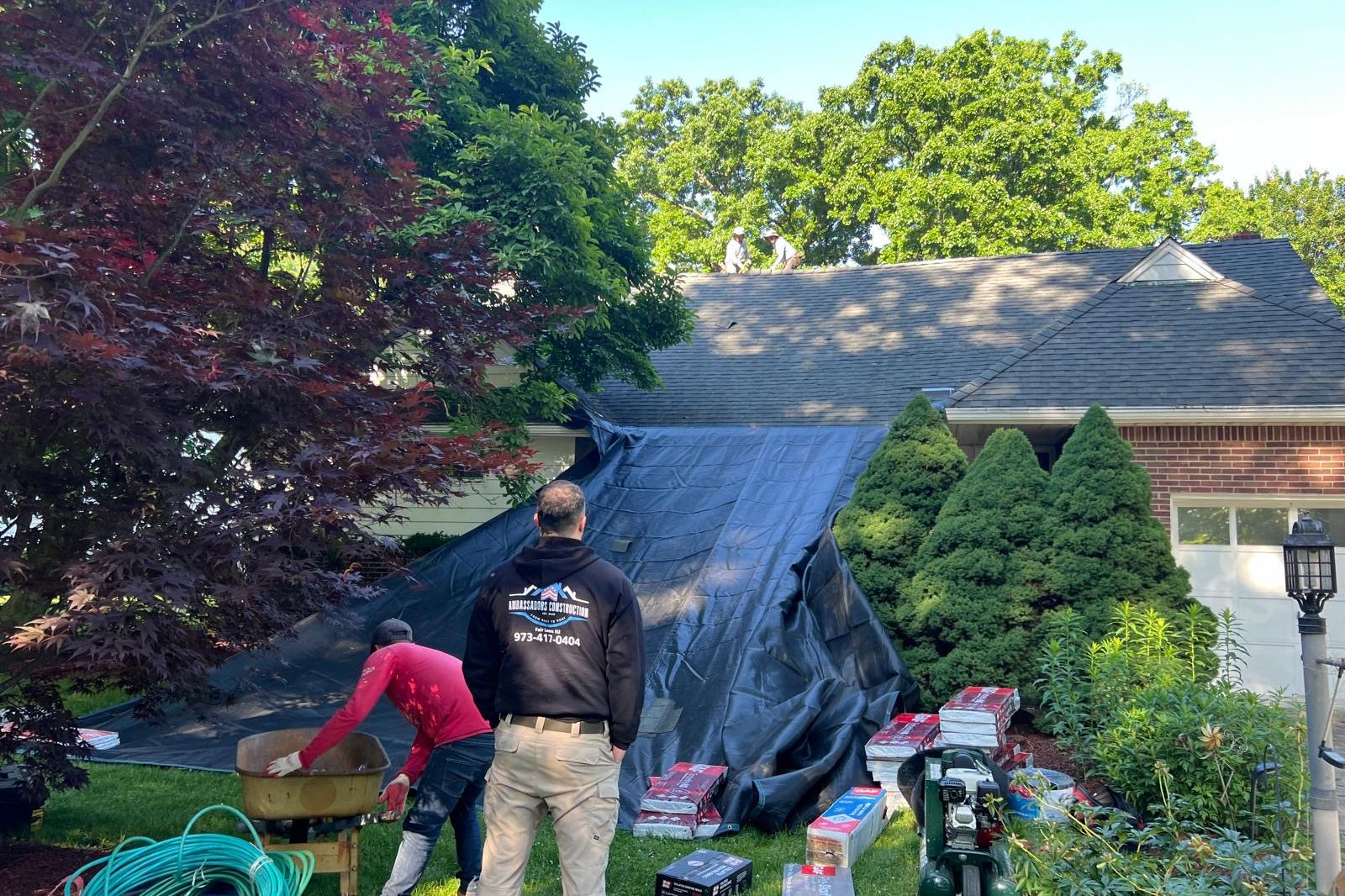 Ambassadors Construction crew clearing tear-off debris during a roof damage repair in New Jersey
