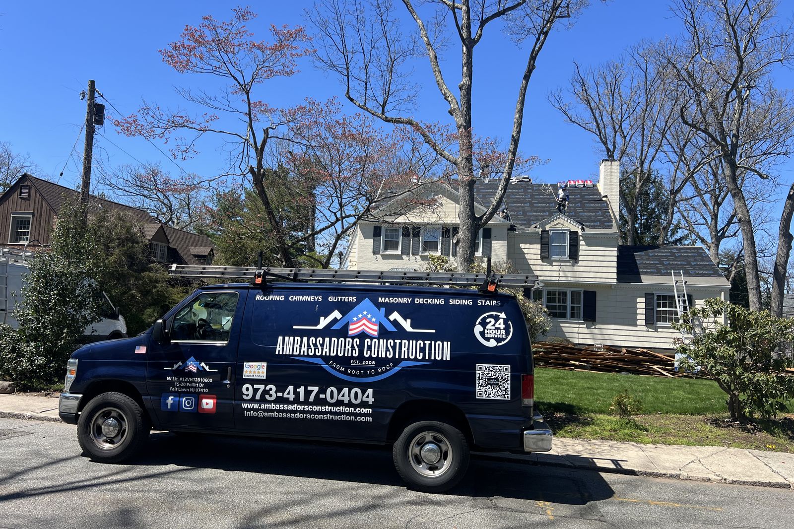 Ambassadors Construction service van parked outside a New Jersey home with new roof underlayment visible