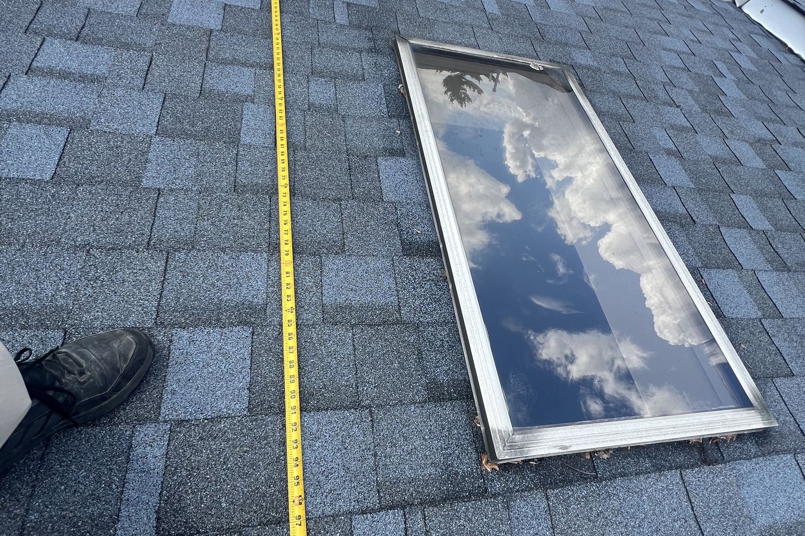Ambassadors Construction measuring an old skylight before replacement on a New Jersey roof