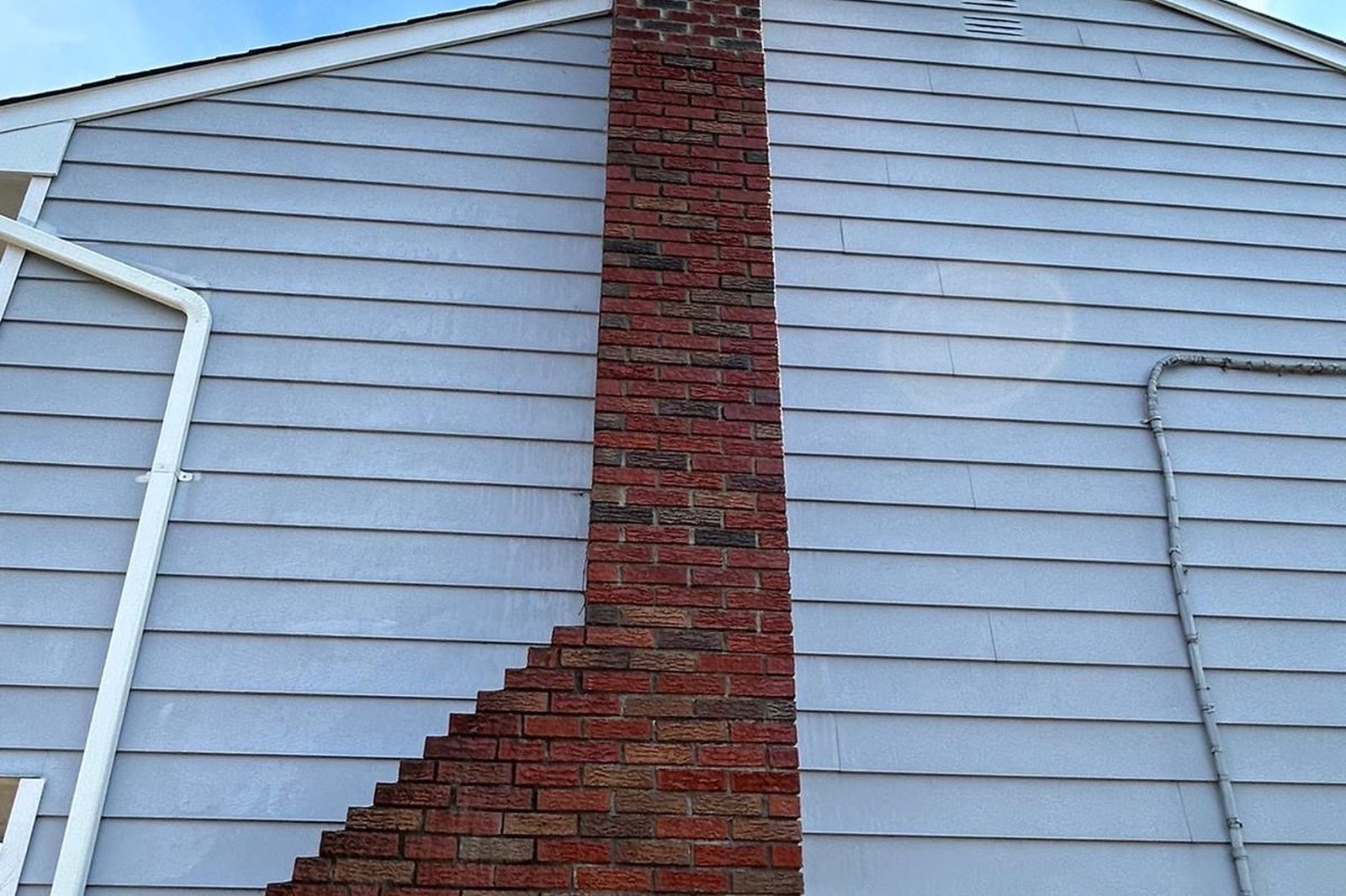 Tall rebuilt brick chimney against a New Jersey home's siding